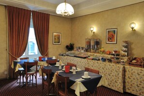 A dining area with tables set for breakfast, a buffet with various food items, and artwork on the walls. - Hotel Moderne Genève (Geneva)