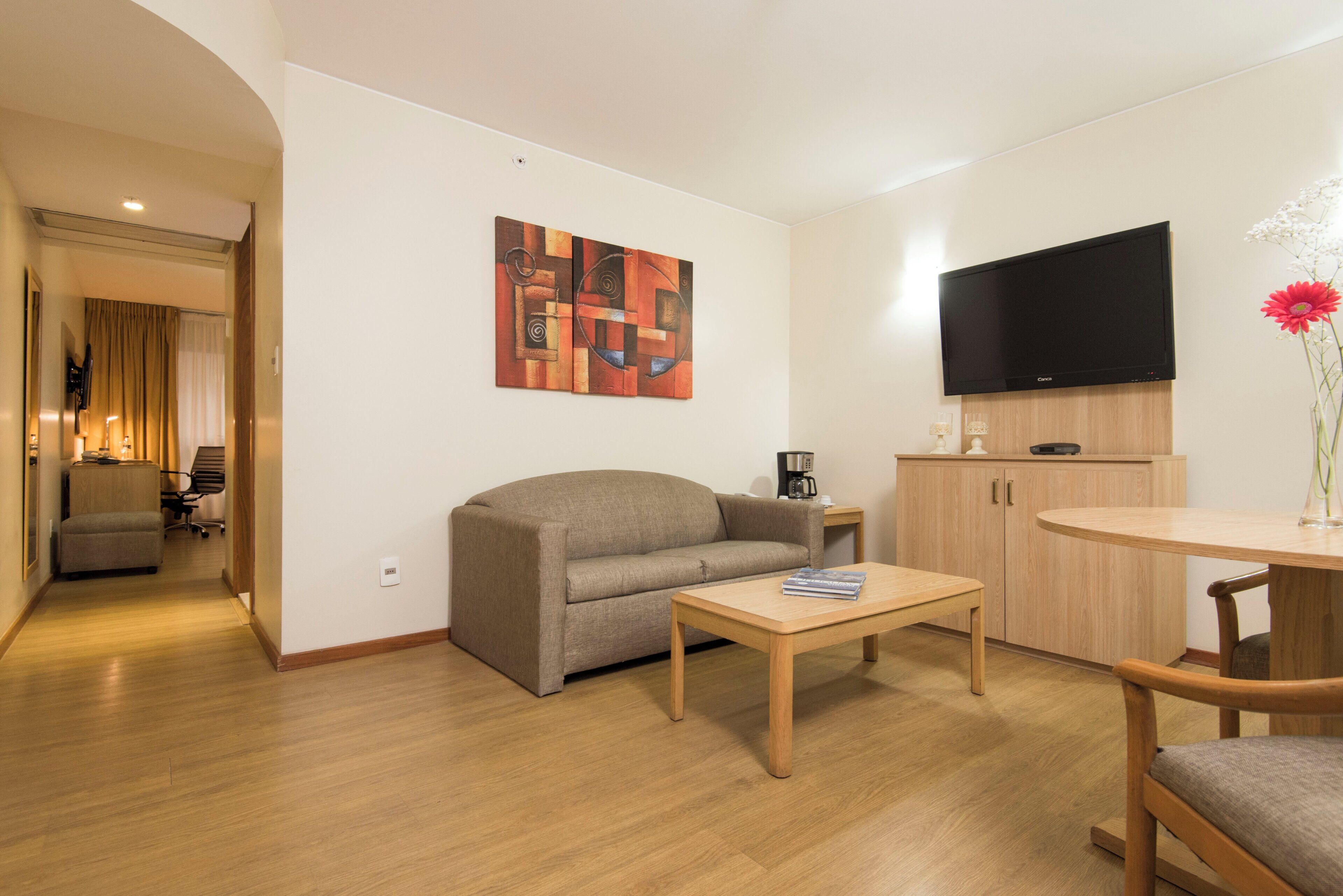 Uma sala de estar moderna com sofá, mesa de centro, TV e um quadro na parede.