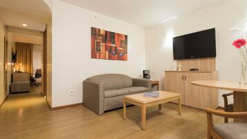 Uma sala de estar moderna com sofá, mesa de centro, TV e um quadro na parede.