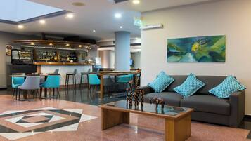 A modern lobby with a bar area, seating, and a large abstract painting.