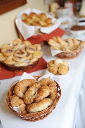A table with various baked goods, including croissants and pastries, arranged in baskets. - Holiday Inn Montevideo by IHG (Montevideo)