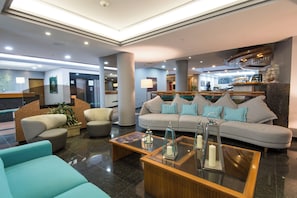 A hotel lobby with a reception desk, seating area, and a bar.