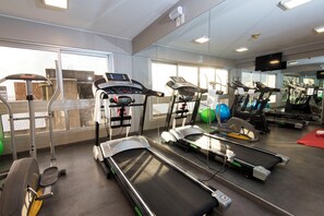 A gym with treadmills, exercise balls, and a mirrored wall.