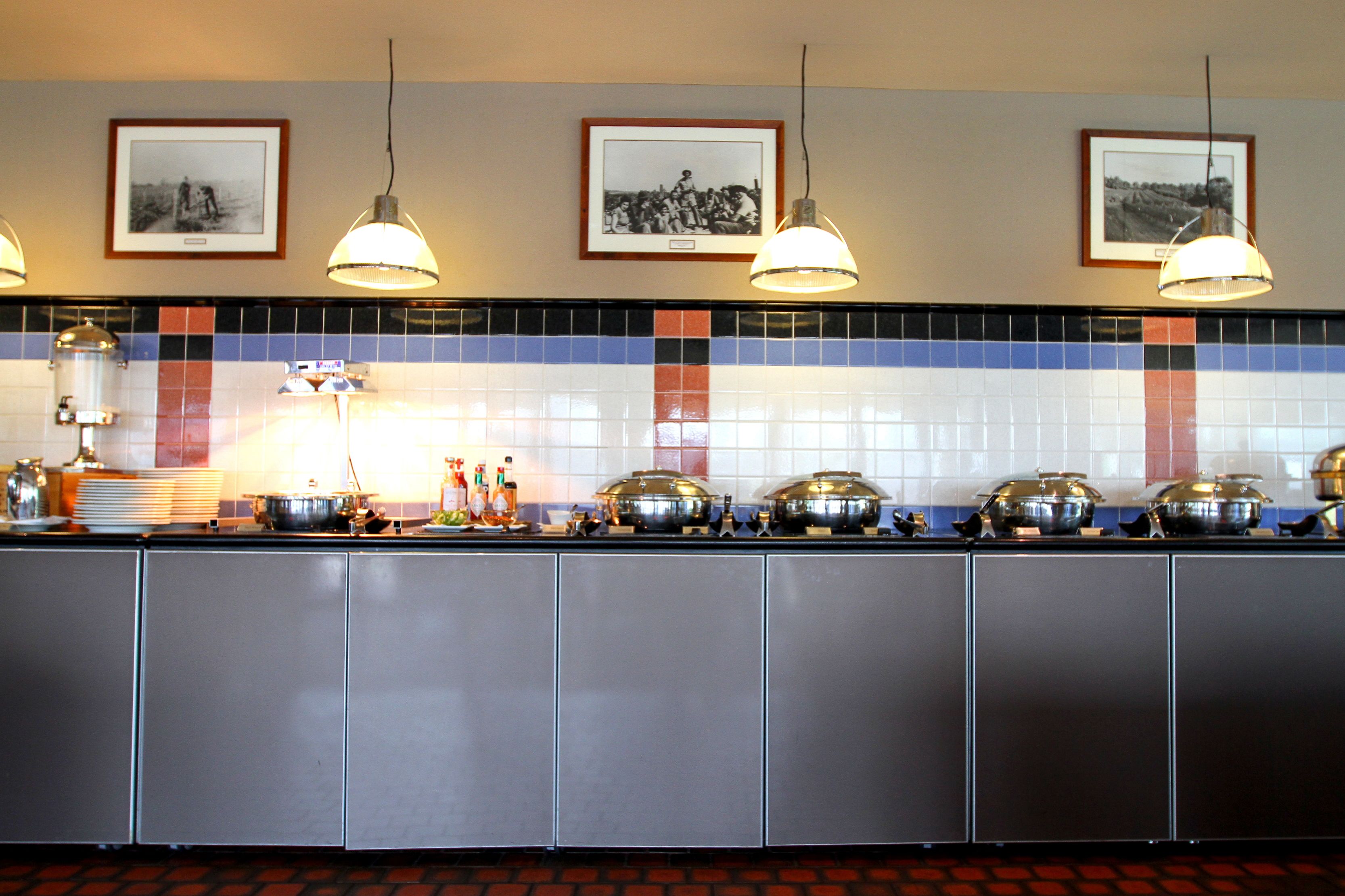 Ein Buffet mit verschiedenen Servierstationen, Deckenleuchten und gerahmten Bildern an der Wand.
