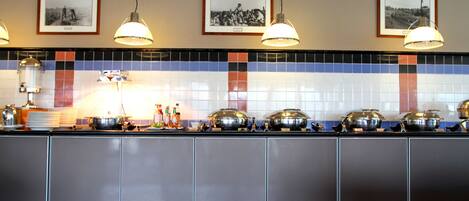 Ein Buffet mit verschiedenen Servierstationen, Deckenleuchten und gerahmten Bildern an der Wand.