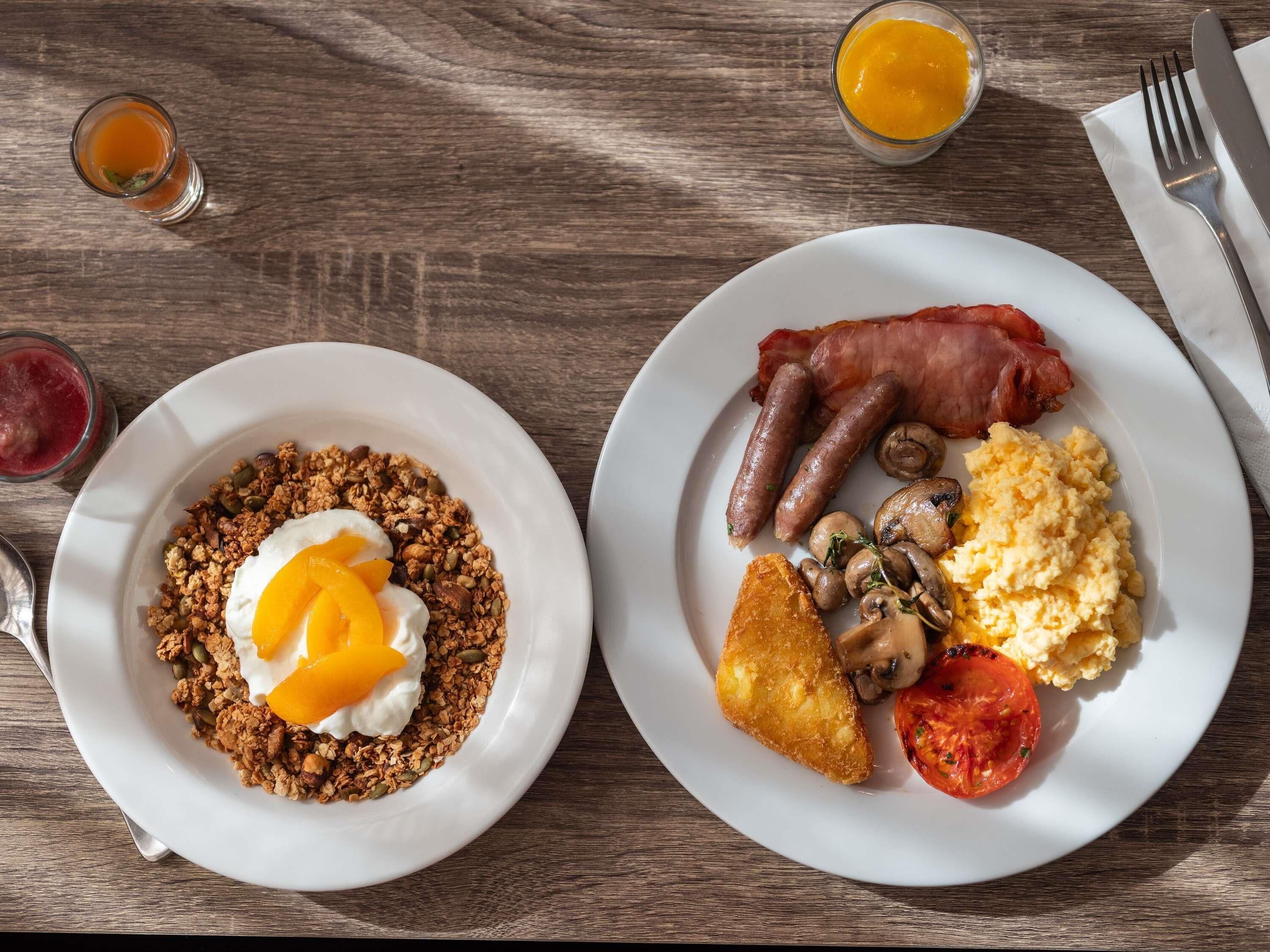 Two plates of breakfast food on a wooden table.