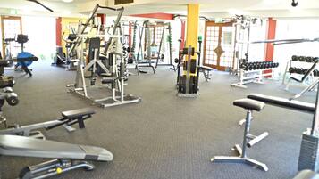 A gym with various exercise equipment, including treadmills, weight machines, and dumbbells.