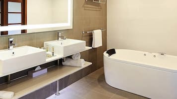 A modern bathroom with two sinks, a large bathtub, and a mirror.