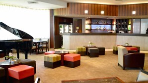 A hotel lobby with a grand piano, a bar area, and seating arrangements. - Novotel Vines Resort Swan Valley (The Vines)