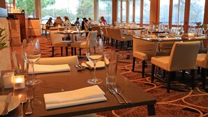 A restaurant with multiple tables set for dining, large windows, and a view of the outdoors. - Novotel Vines Resort Swan Valley (The Vines)