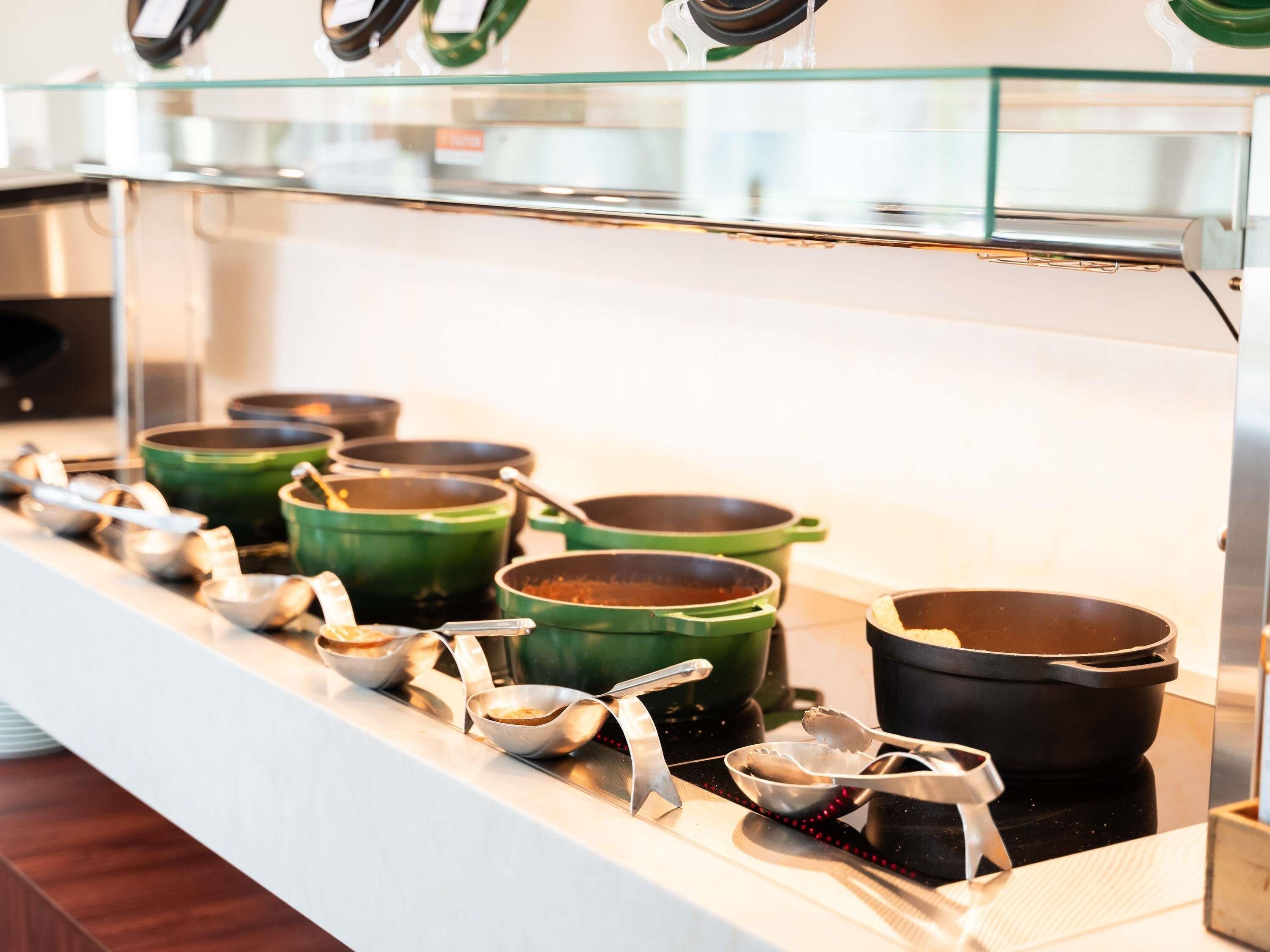 A buffet line with various pots and bowls on a counter.