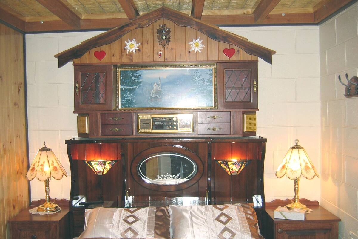 A bedroom with a wooden headboard, a large mirror, and two bedside tables with lamps.