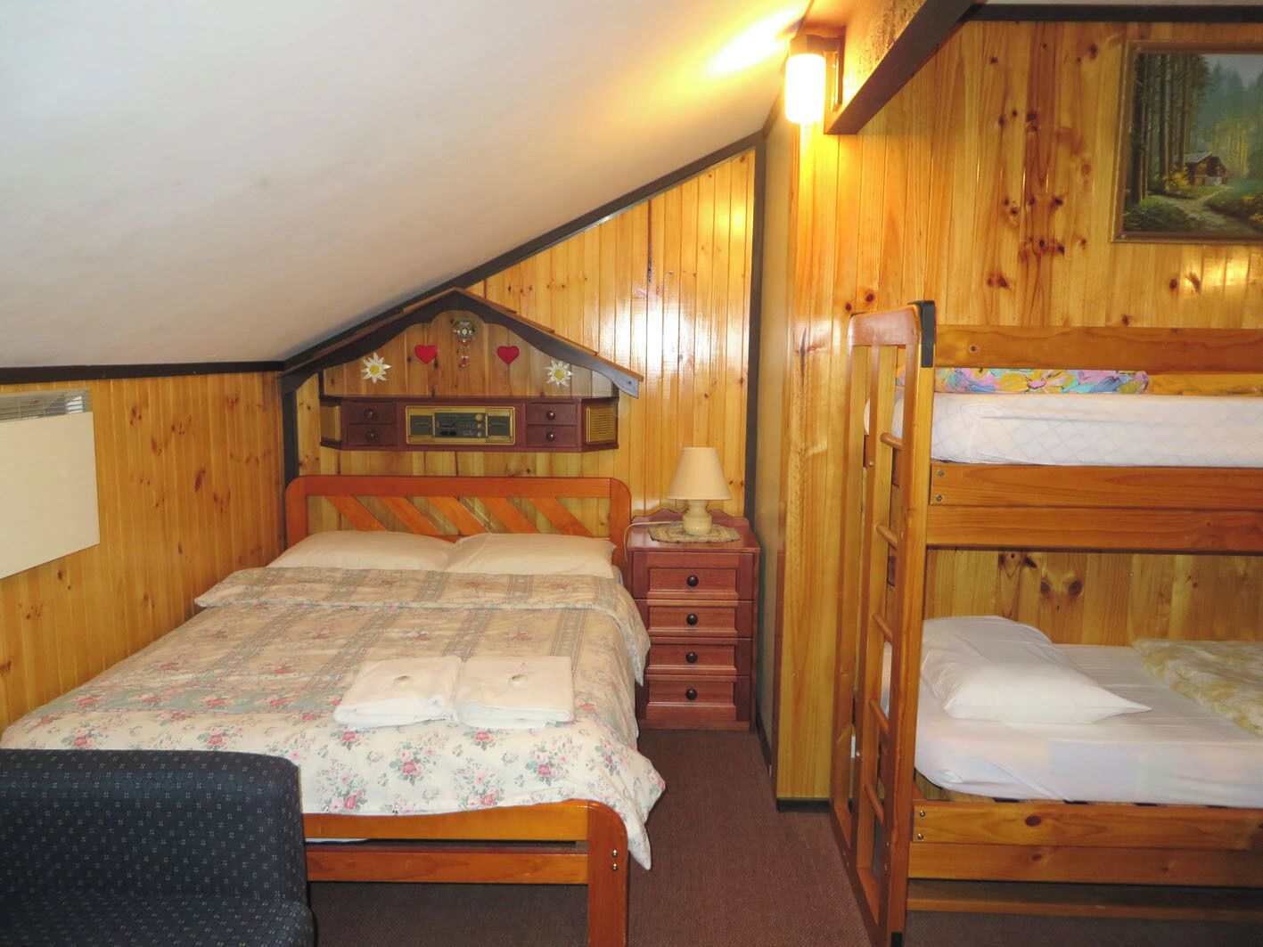 A wooden cabin bedroom with a bunk bed, a single bed, and a dresser with a radio.