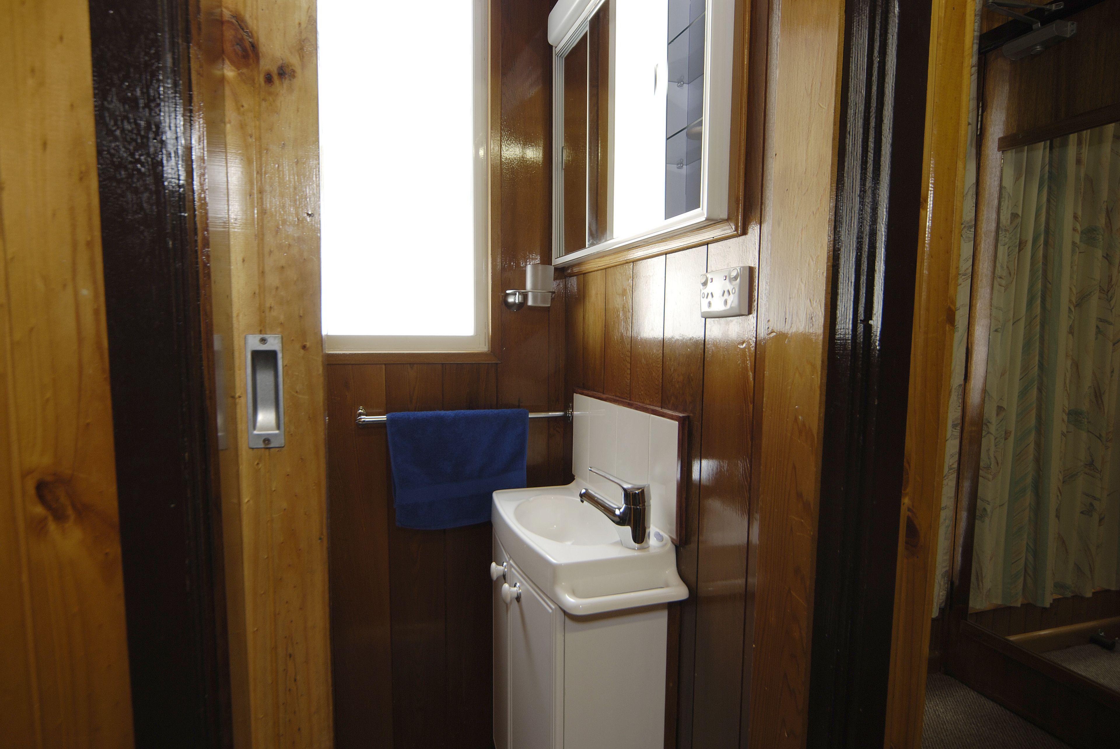 A wooden bathroom with a white sink and a mirror above it.