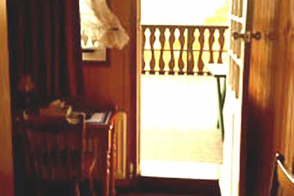 A narrow hallway with a wooden door leading to a balcony.
