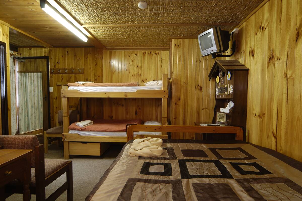 A wooden cabin room with bunk beds, a television, and a small desk.