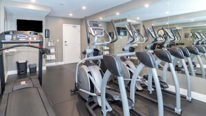 Une salle de sport équipée de tapis de course, d’un vélo d’appartement et d’un rameur.