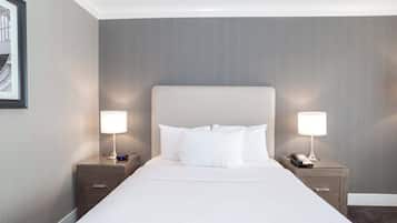 Une chambre d’hôtel avec un grand lit, deux tables de chevet avec des lampes et un tableau encadré au mur.