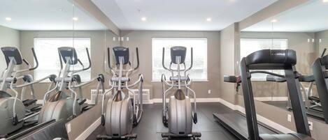 Un gimnasio con cintas de correr, elípticas y bicicletas estáticas.