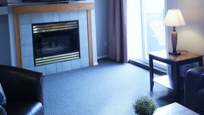 A modern living room with a fireplace, a flat-screen TV, a lamp, and a seating area. - Canadian Rockies Chalets by Trilink (Canmore)