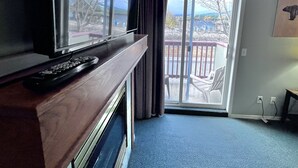 A living room with a fireplace, a television, and a sliding glass door leading to an outdoor area. - Canadian Rockies Chalets by Trilink (Canmore)