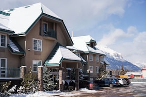 A multi-story hotel with a snow-covered roof and a mountain backdrop. - Pocaterra Inn and Waterslide (Canmore)