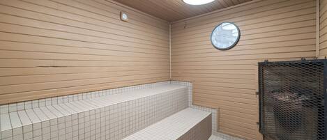 Une salle de bain avec des murs lambrissés en bois, un sol carrelé, un lavabo avec un miroir et un espace douche.
