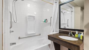 A modern bathroom with a bathtub, shower, and sink.