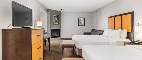 Habitación de hotel con dos camas, televisión, escritorio y chimenea.