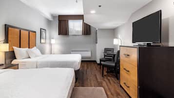 Une chambre d’hôtel avec deux lits, un bureau, une télévision et une commode.