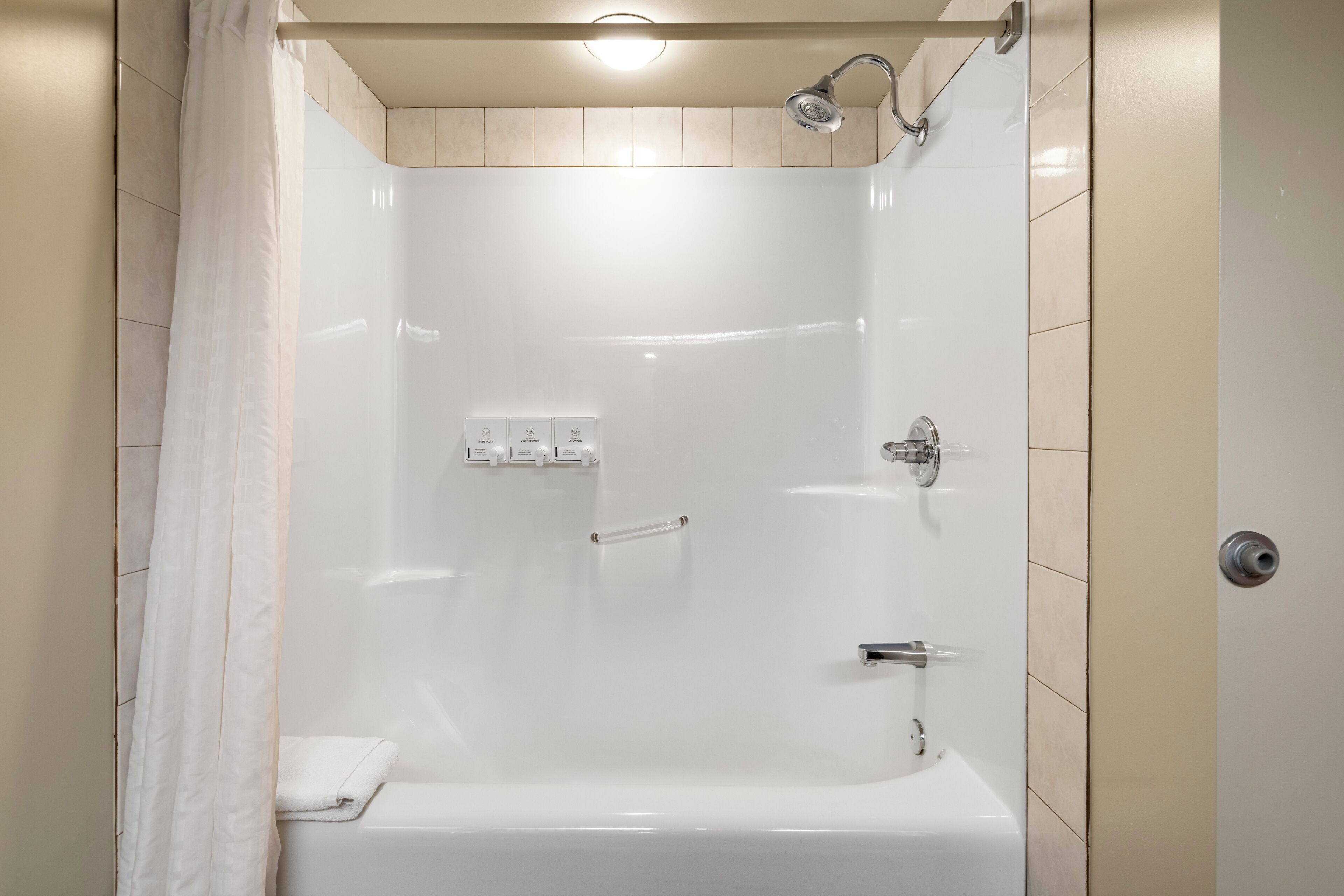A modern shower with a glass door, a handheld showerhead, and a handheld shower attachment.