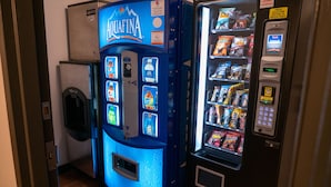 Un distributeur automatique de couleur bleue, proposant un assortiment de collations et de boissons.