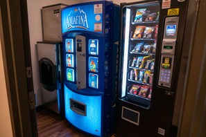 Un distributeur automatique de couleur bleue, proposant un assortiment de collations et de boissons.