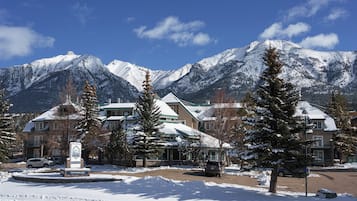 A hotel with a sign indicating breakfast is included, surrounded by snow-covered mountains and trees.