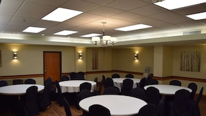 Une salle de conférence dotée de plusieurs tables rondes et de chaises, et équipée de luminaires au plafond et d’appliques murales.