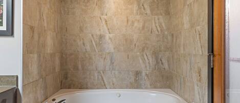A bathroom with a freestanding bathtub, marble walls, and a framed picture on the wall.
