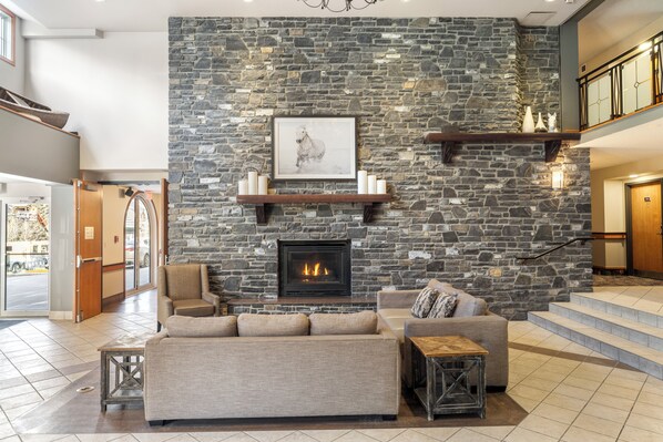 A modern living room with a stone wall, fireplace, and a sofa.
