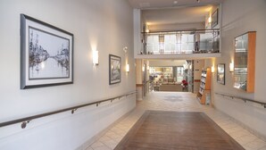 A spacious hotel corridor with a wooden floor, framed artwork on the walls, and a second-floor balcony. - Pocaterra Inn and Waterslide (Canmore)