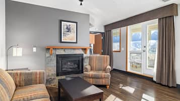 A living room with a fireplace, a sofa, a chair, and a table.