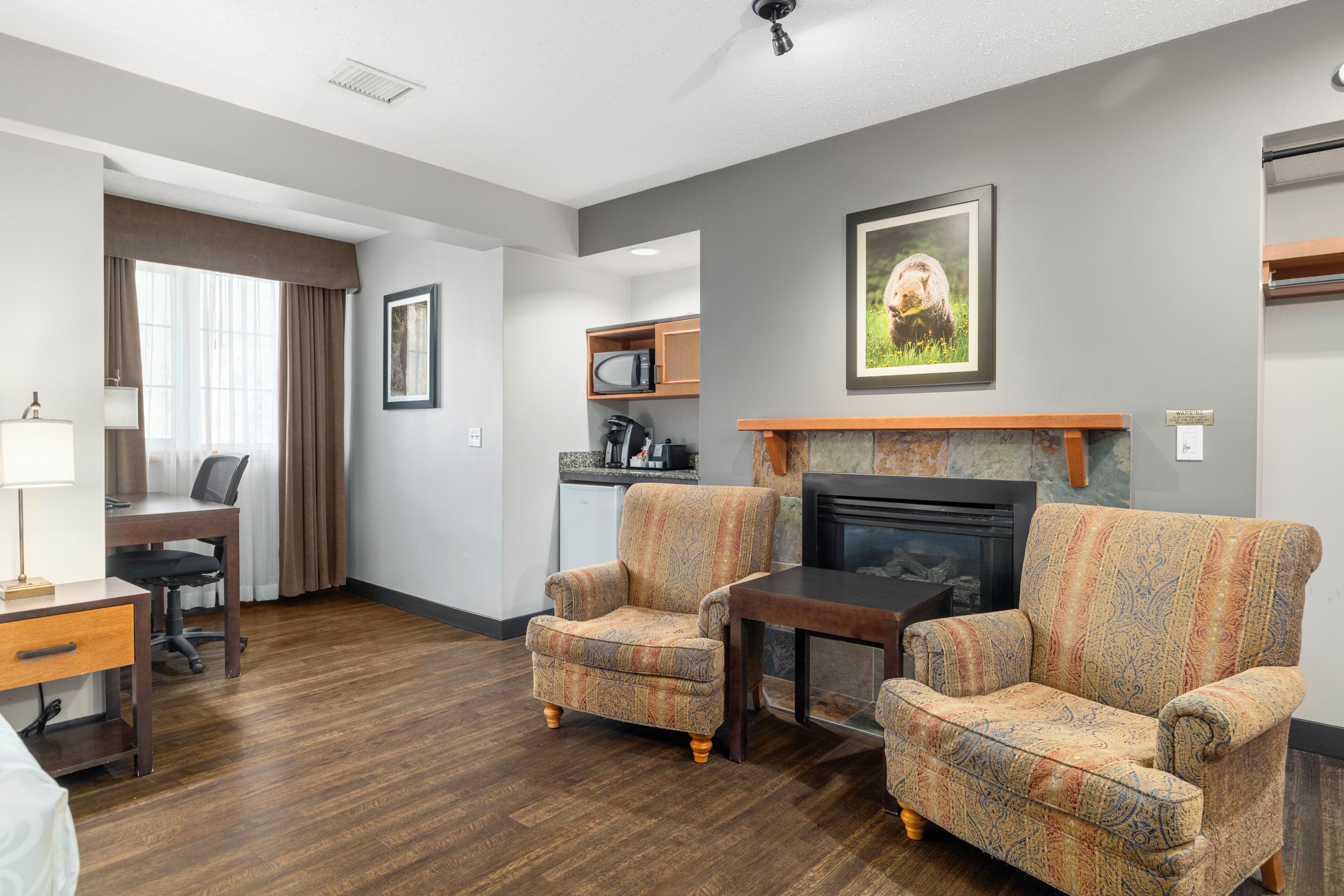 A hotel room with a living area, a dining area, and a kitchenette.