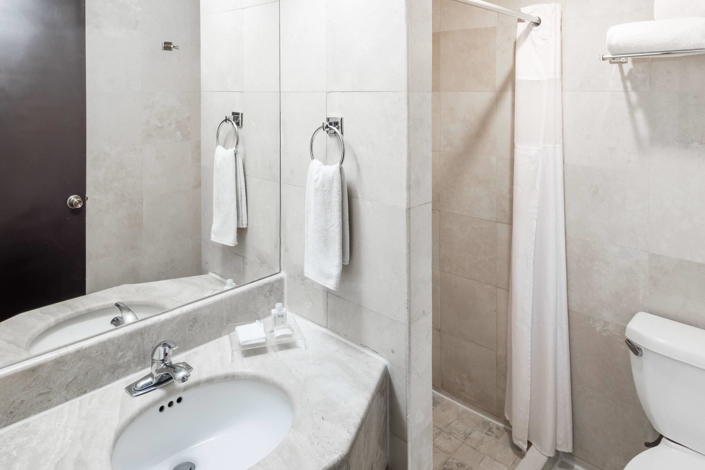 A modern bathroom with a sink, mirror, and toilet.