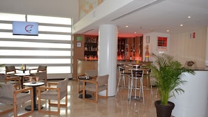 Un moderno vestíbulo de hotel con zona de bar, asientos y una gran planta en maceta.
