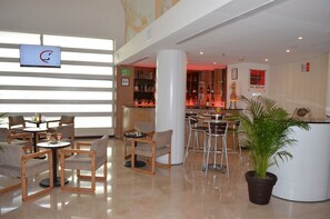 Relax in the stylish lobby of La Grange, featuring a reception area with a bar, comfortable seating, and a lush potted plant.