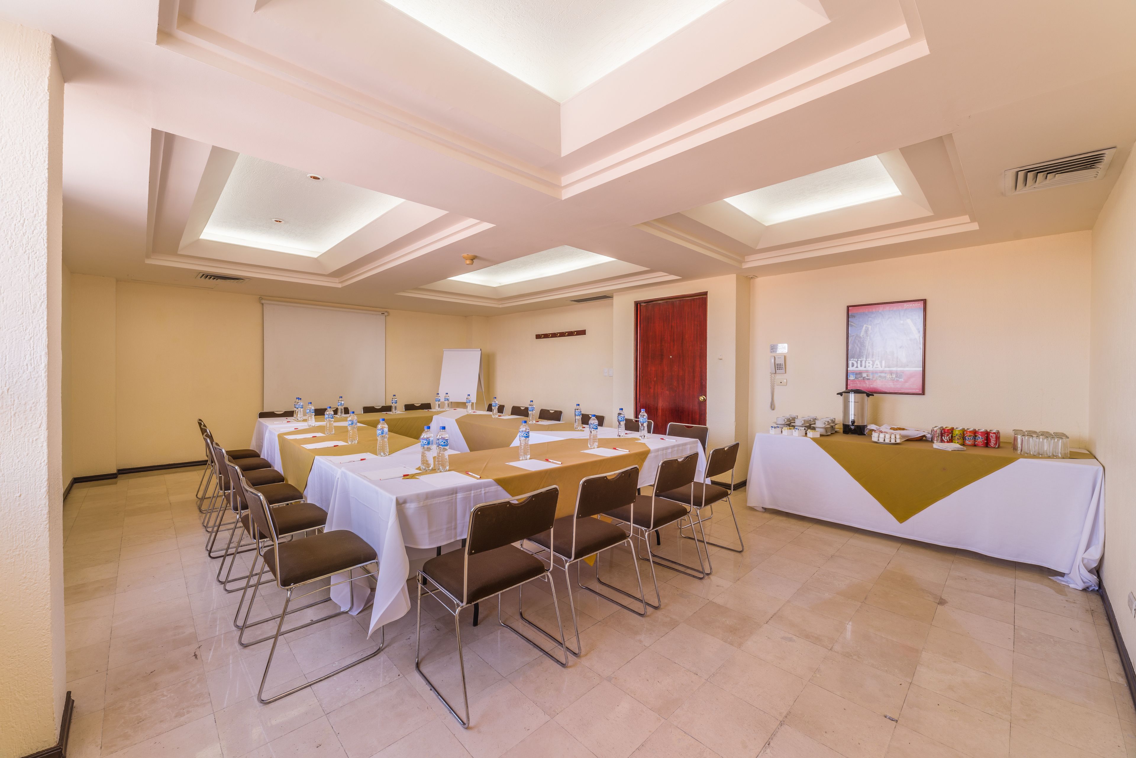 Un salón de conferencias con mesas y sillas, una pizarra y una puerta roja.