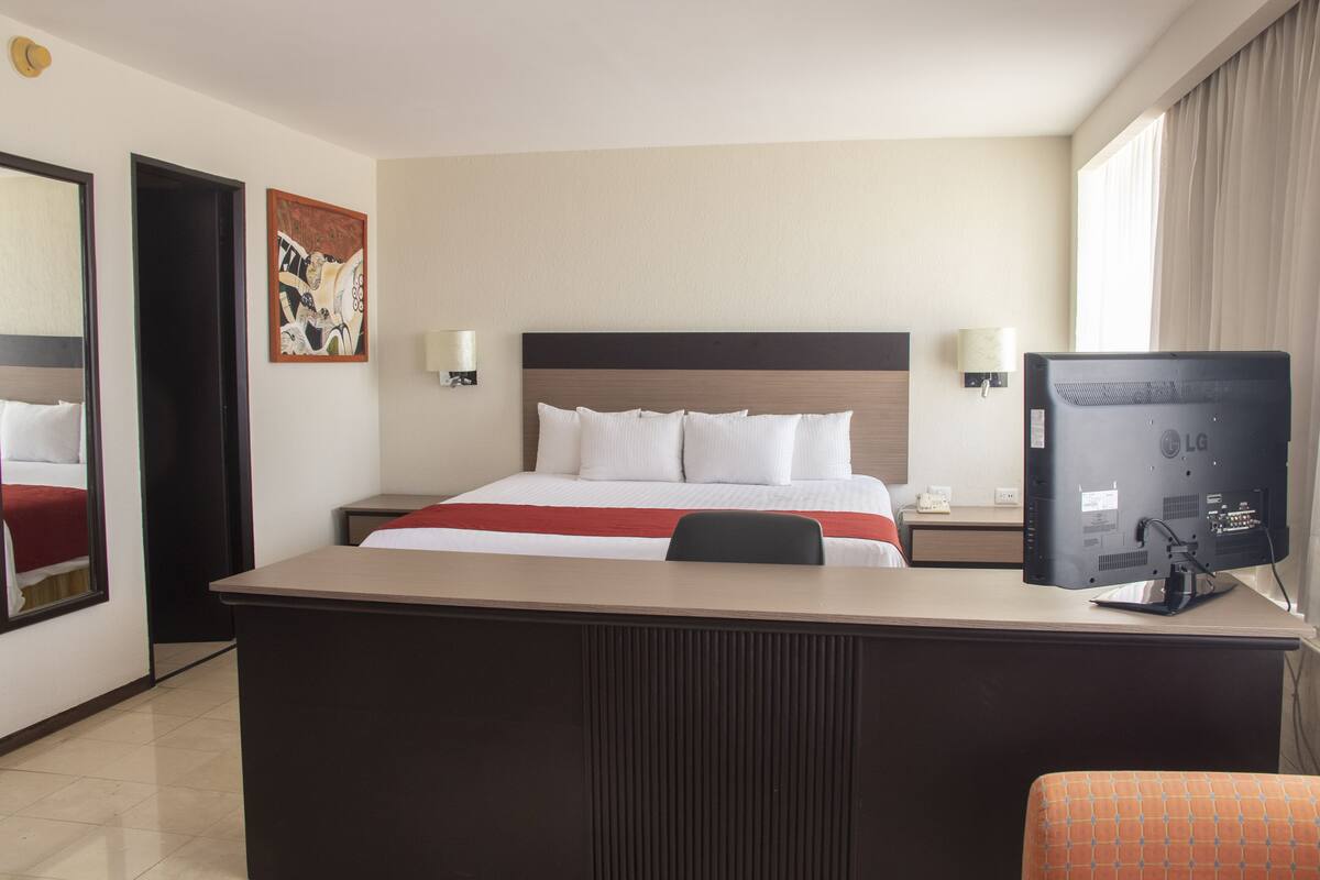 Una habitación de hotel con cama, escritorio y televisor.