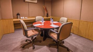 A conference room with a round table, four chairs, a coffee station, and a vase with decorative sticks.