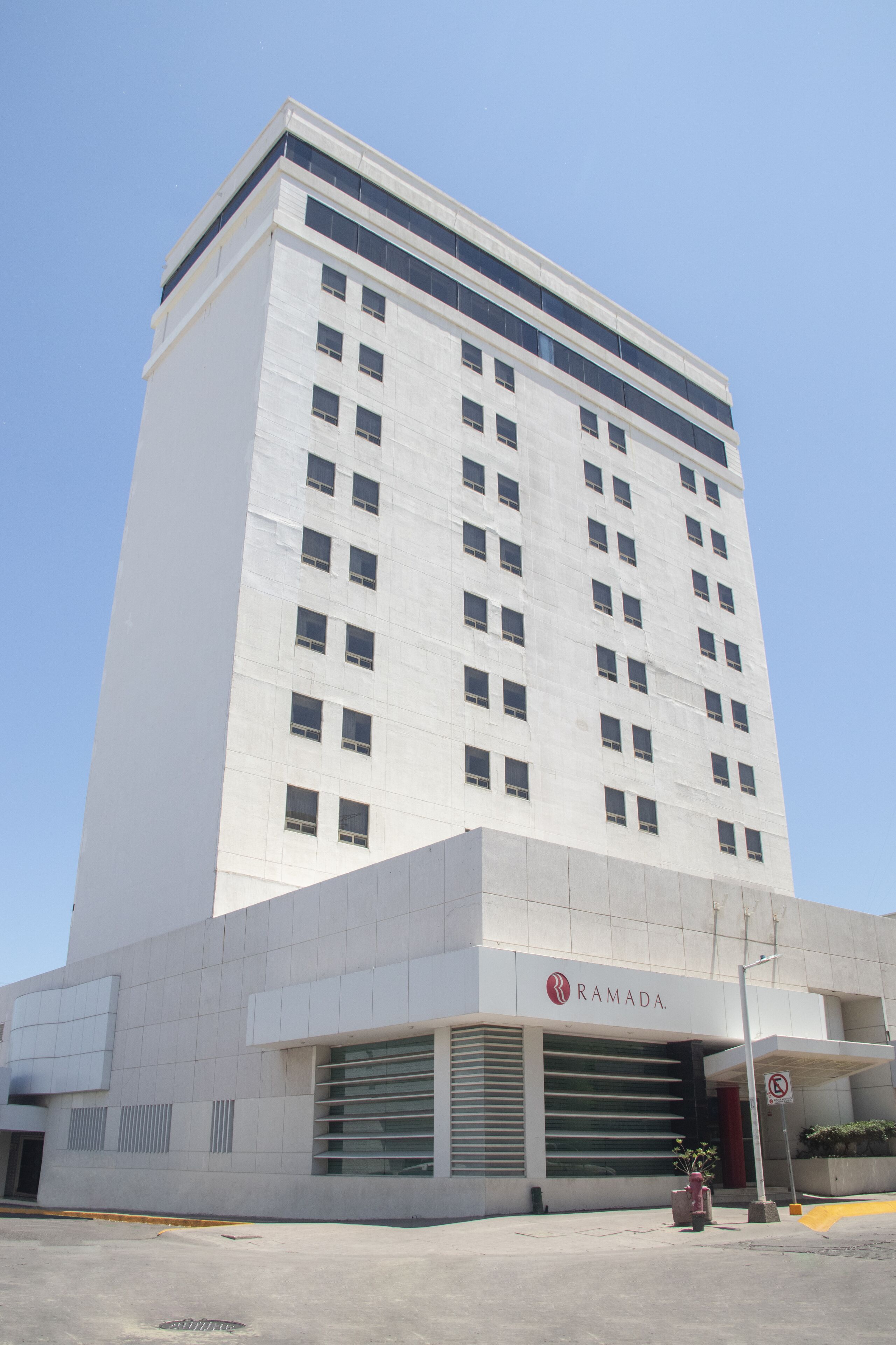 A tall, white building with the name "RAMADA" on the ground floor.