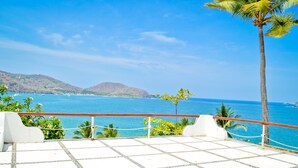 A terrace with a view of the ocean and hills.
