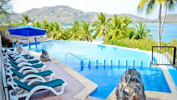 Una piscina con sillones de descanso y vistas al mar.