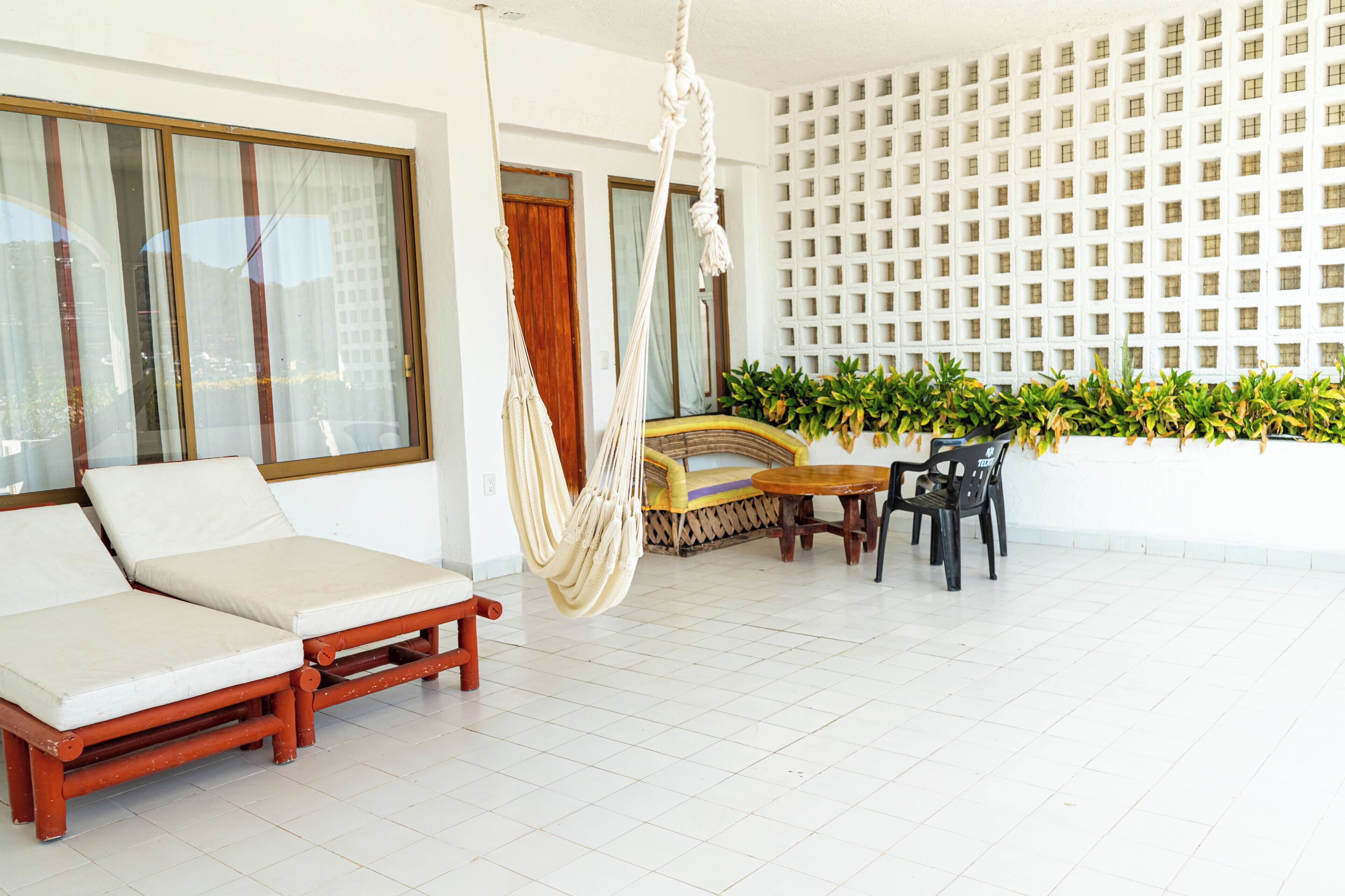 A room with a sofa, a hammock, a table, and chairs.